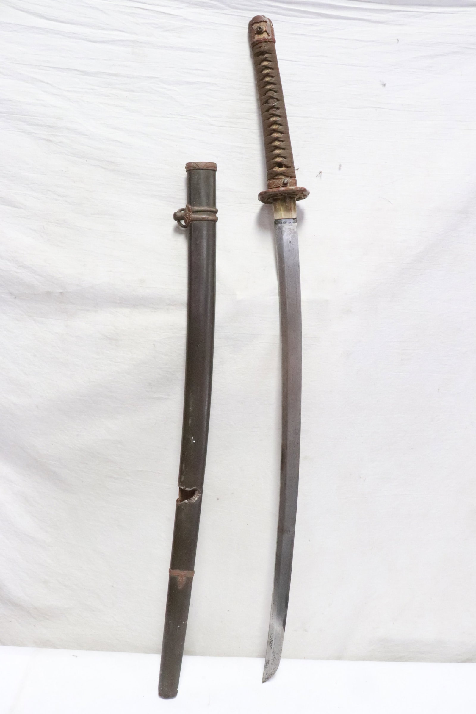A WWII Japanese NCO samurai sword: A WWII Japanese NCO samurai sword, the scabbard has a bullet strike mark, but he blade is in good condition, 39.8"L