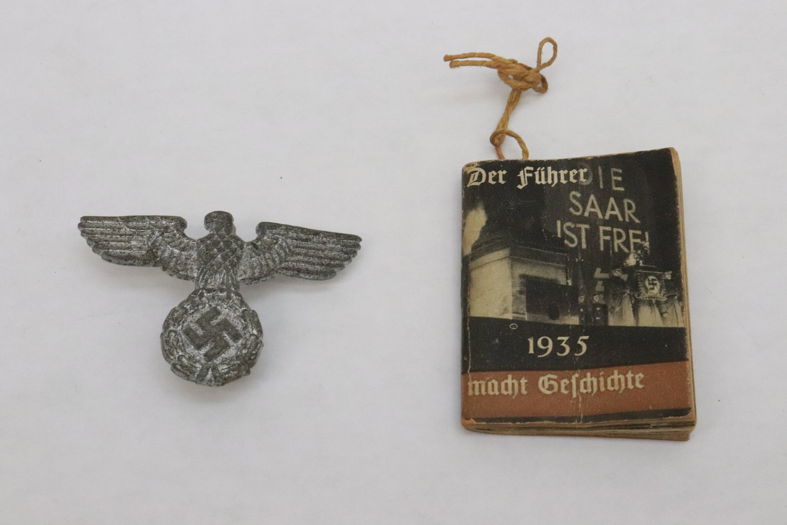 2 pieces: 2 pieces; a German WWII cap insignia (1.2"x1.8"x0.65"), and a German 1935 miniature propaganda booklet