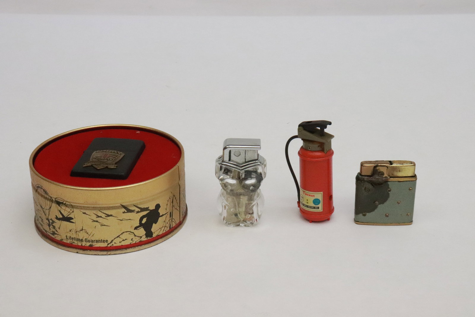 4 lighters: 4 lighters; Prince Gardner (damage) (1.8"x1.6"x0.4"), a Zippo D-day memorabilia lighter (2.2"x1.5"x0.65" (box:2.1"x4.25"dia)), and an interesting nude motif lighter (2.5"x1.35"x1.2")