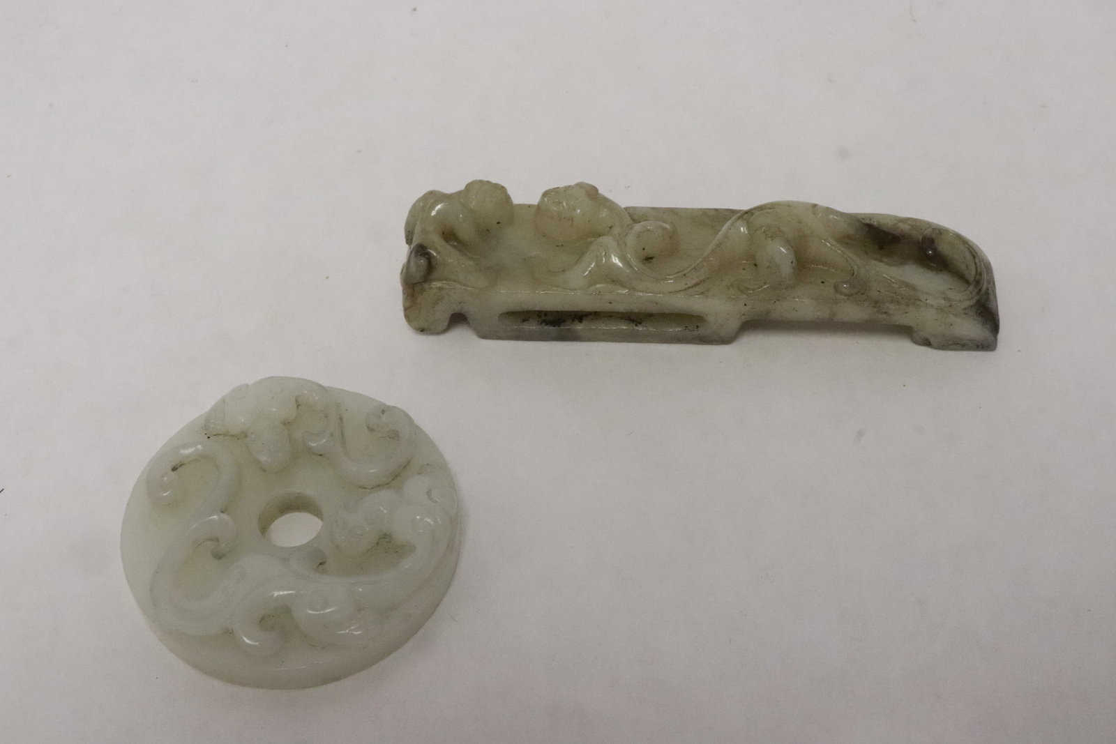 a jade carved belt buckle, & a jade like stone disc: 2 pieces; a jade carved belt buckle (3.9"x0.8"x0.8"), and a jade like stone disc (0.6"x2"dia)