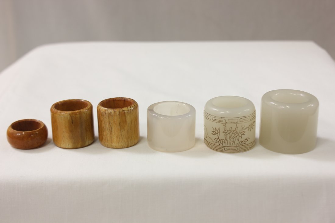 6 Chinese archer rings: 6 Chinese archer rings, 2 white jade (1.4"Hx1"0.d., 1.25"Hx1.4"o.d.), 3 ivory (1.15"Hx1.1"o.d., 1.1"Hx1.15"o.d, 0.55"Hx1.1"o.d.), and one Peking glass (1"hx1.35"o.d.)