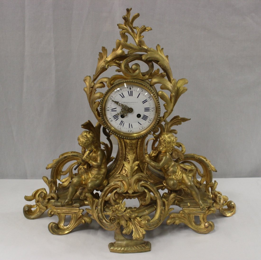 A French antique gilt bronze table clock: A French antique gilt bronze table clock, the dial signed Abercrombie & co., the gilt bronze depicting 2 angels in base, a beautiful example (one back leg missing), 21.25"Hx23"x8.75"