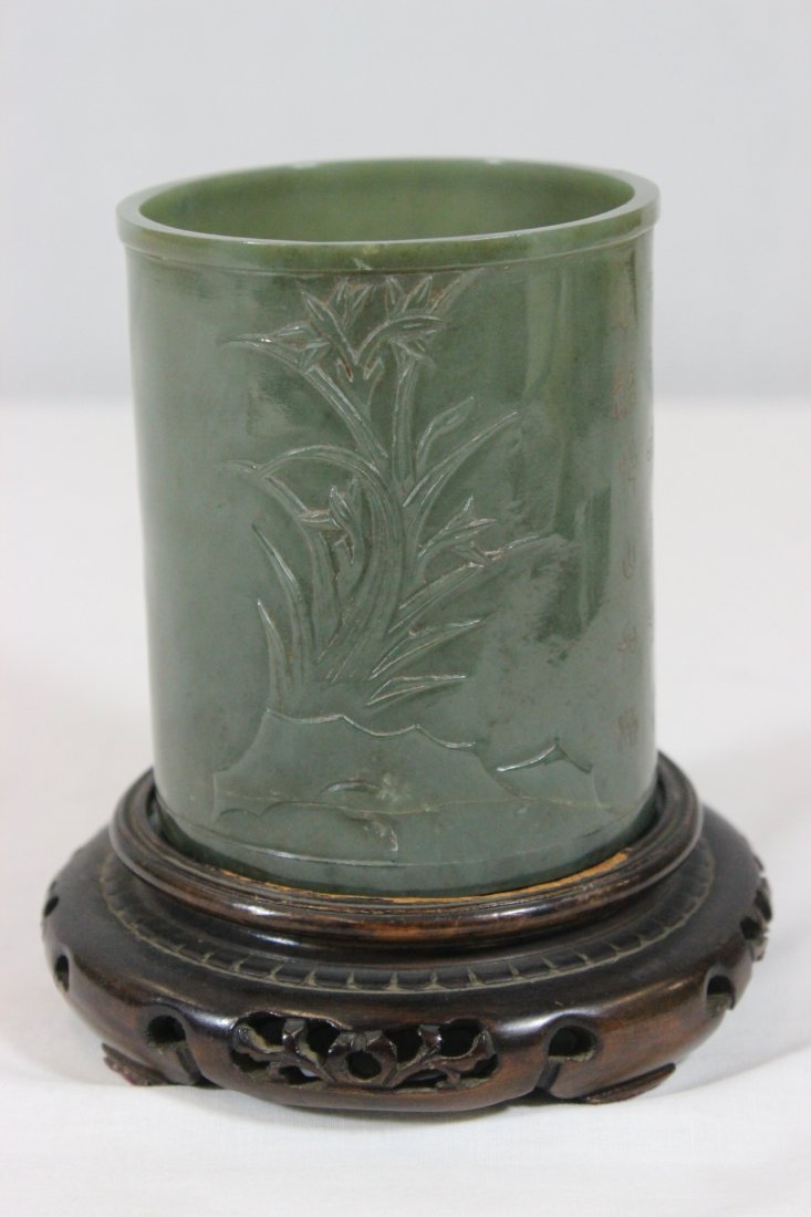 A celadon jade carved brush holder: A celadon jade carved brush holder (3.85"Hx3.3"dia) decorated with flowers in relief and engraved with calligraphy