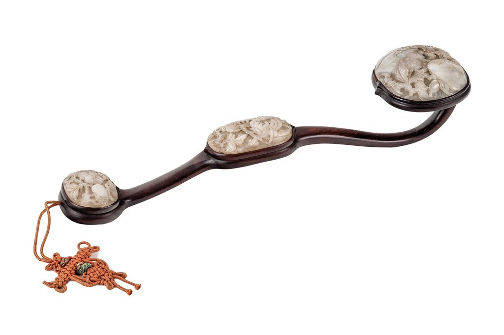 A Chinese hardwood and jade Ruyi Sceptre, probably: A Chinese hardwood and jade Ruyi Sceptre, probably late Qing Dynasty, 19th/20th century with three grey/ white jade plaques inset in a sectional hardwood frame, each one carved with leafing fruit 42cm