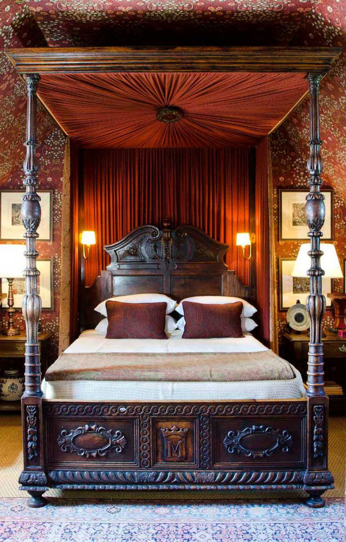 An oak four poster canopy queen size bed, German, 19th: An oak four poster canopy queen size bed, German, 19th century with applied cresting and cartouches upholstered in maroon pleated linen and side curtains with attached electrified side sconces togethe
