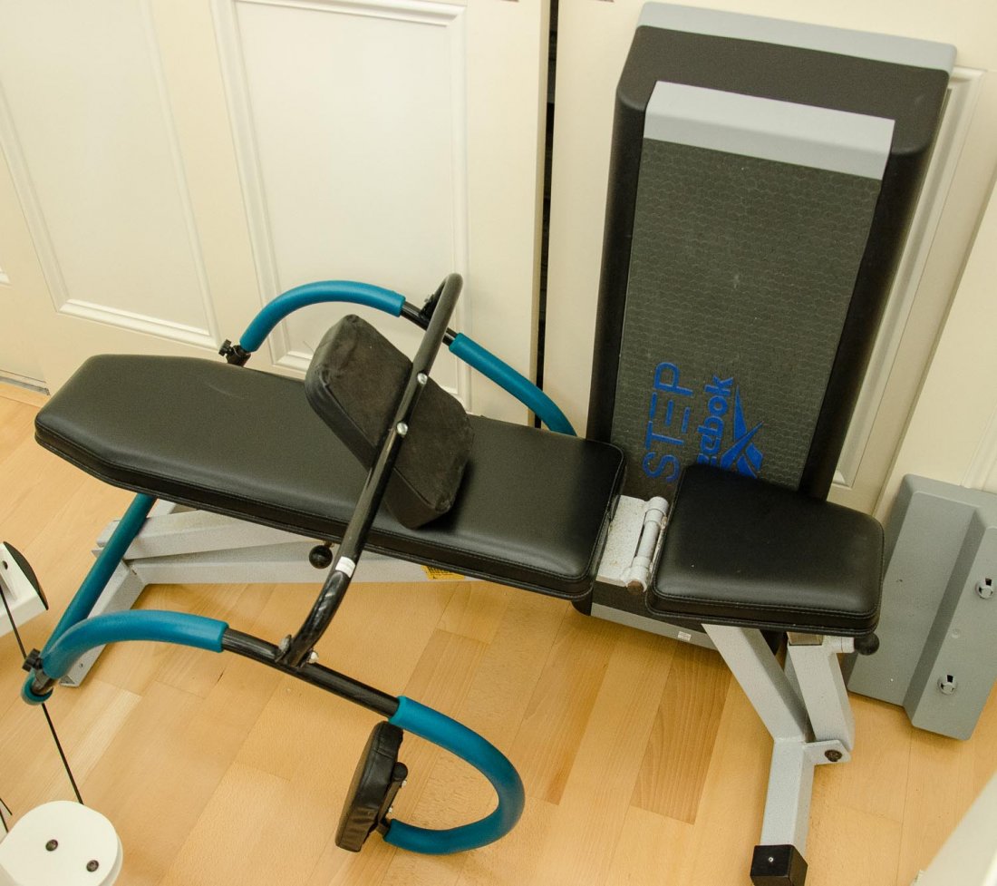 A Hoist Fitness Systems weights bench: A Hoist Fitness Systems weights bench together with a Reebok excercise step and an Ab-Curler