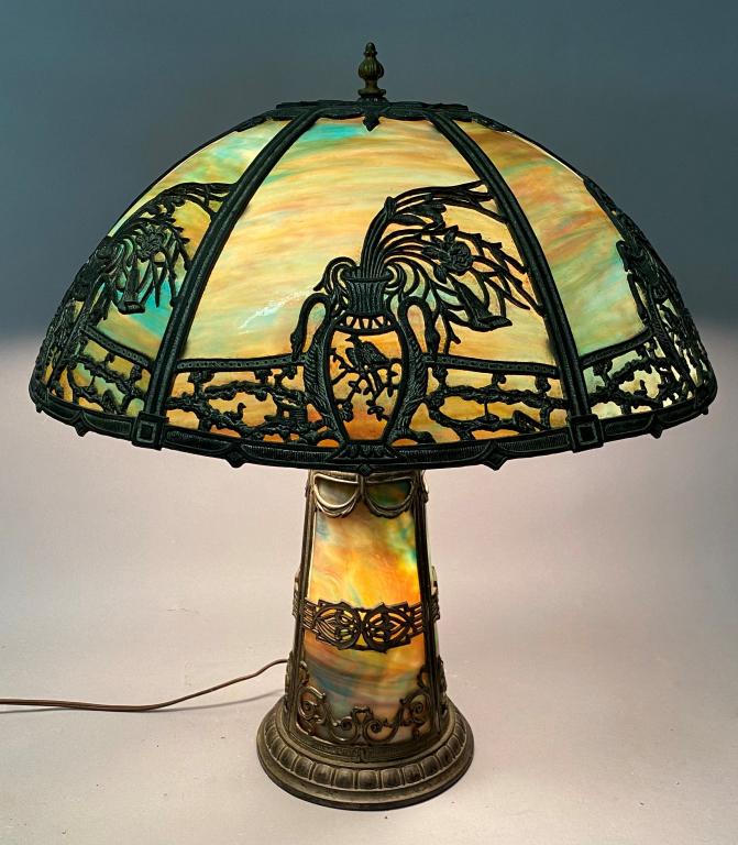 RAINBOW SLAG GLASS 20" PANEL LAMP: WITH ASIATIC DESIGN OF FLOWERS IN A VASE AND BIRDS, ON A LIGHTHOUSE FORM BASE; DIAMETER OF SHADE IS 20", APPROX. 21" TALL TO FINIAL; ONE PANEL REPLACED