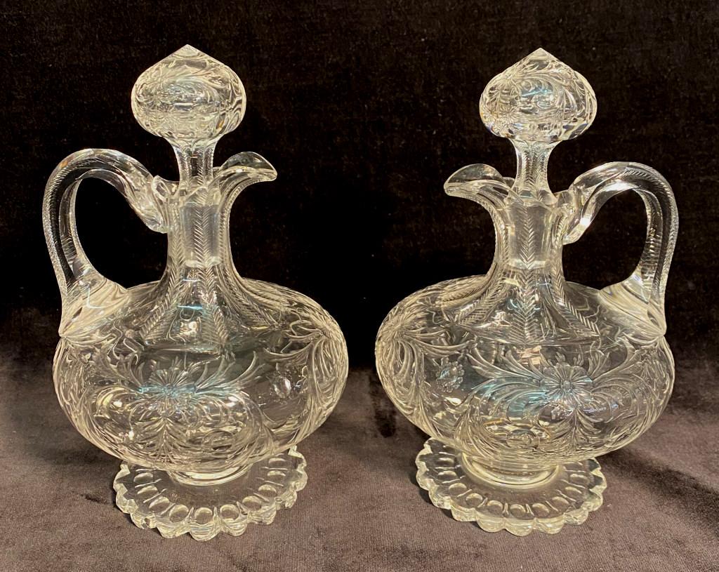 PAIR HAWKES ROCK CRYSTAL ENGRAVED PEDESTAL CRUETS: WITH MATCHING PATTERN CUT STOPPERS, SUPERBLY DETAILED FEATHERING TO EDGES OF FLUTING; BRIGHT CLEAR BLOWN BLANKS (POSSIBLY STEUBEN)BOTH STOPPERS AND BOTTLES ARE SIGNED, MINOR TINY FLEA BITES AT RIM FRO