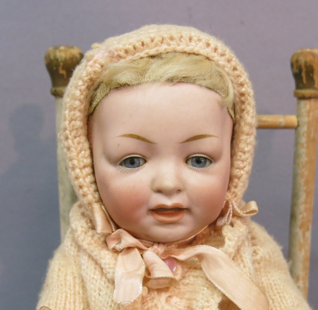 J.D. KESTNER CHARACTER BABY DOLL: #211; BISQUE SOCKET HEAD WITH SLEEP EYES & OPEN/CLOSED MOUTH; COMPOSITION BODY JOINTED AT SHOULDERS & HIPS; SMALL COMPOSITION CRACKS AT NECKLINE; 12" LONG; COMES WITH SMALL WOODEN CHAIR