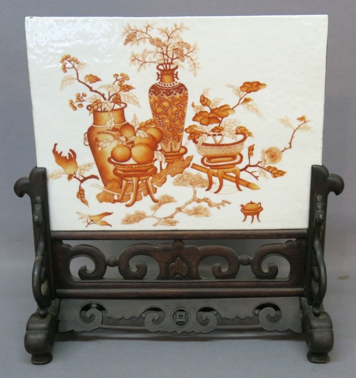 CHINESE PORCELAIN PLAQUE OR TABLE SCREEN: IN CARVED WOODEN STAND; PLAQUE MEASURES 10" X 13 1/2"; THERE IA A 1/2" CHIP ON THE TOP EDGE ON THE REVERSE SIDE, WOODEN STAND HAS BEEN REGLUED IN TWO OR THREE SPOTS