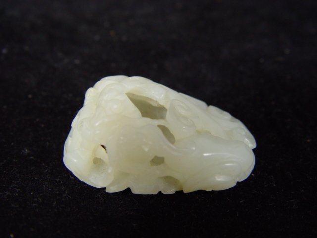 Fine 19th Century White Nephrite carving: A fine white nephrite toggle with hallow inside, pierce-carved to depict two mystic Qilin animals fighting over a linzi fungus in clouds, from the 19th Century. This carving is 2 inches long and 1 inc