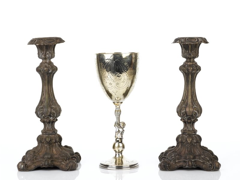 Pair of Victorian Continental Silver Candlesticks: in the Rococo style, with decorative scrollwork and leaf motifs and wooden enforced bases, together with a Victorian engraved chalice with figural support (3) each candlestick height 28 cm, chalice he