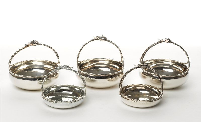 Collection of Plated Table Accessories: comprising five bon bon dishes in the shape of baskets with floral motif detail on handle, two smaller and three larger, together with a pair of fluted bowls with gilt interiors (7) (A/F) The Barbara