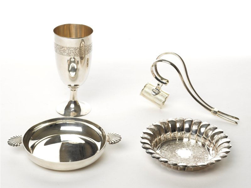 Collection of Silver Table Accessories: comprising a quaich with twin handles in the shape of shells, together with a silver chalice, bottle holder and wine coaster (4) The Barbara Sheridan Donnay and the Late Gilbert J. Donnay Collection q