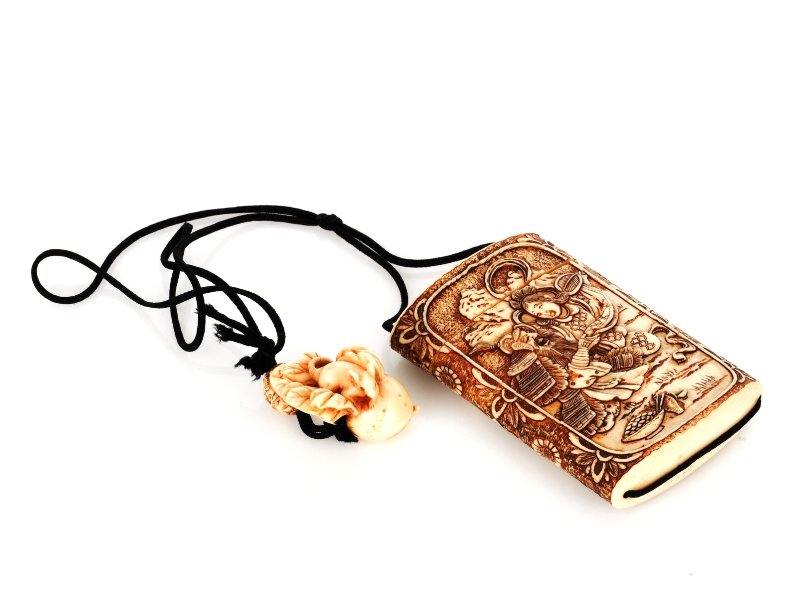 Japanese Carved Ivory Inro: a four piece carved pendant depicting a scene of two traditional figures on one side and three traditional figures on the other, decorated with floral patterned border, together with two other pendant