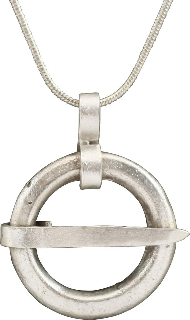 VIKING PROTECTIVE BROOCH NECKLACE, C.870-1066: Cambridgeshire, England. Circular bronze, slightly under 1" diameter of rounded faces front and back, and tapered cross pin. Surface textured from burial. Worn in numbers on the surface of the jerkin,