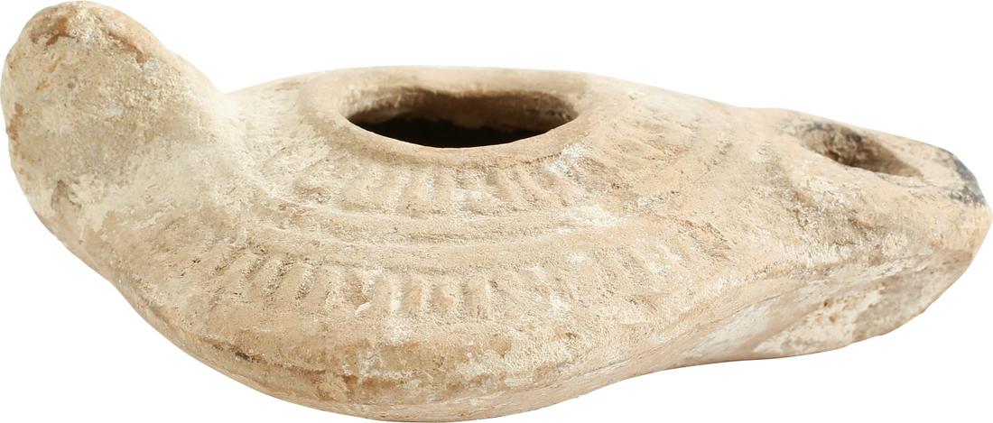 ANCIENT HOLY LAND OIL LAMP, 2ND-5TH CENTURY AD: 3 ¾” length, buff terracotta of broad rounded form with back thumb nub and raised lip filler. Decorated in two bands of radial rays with raised borders. The spout with black char from the