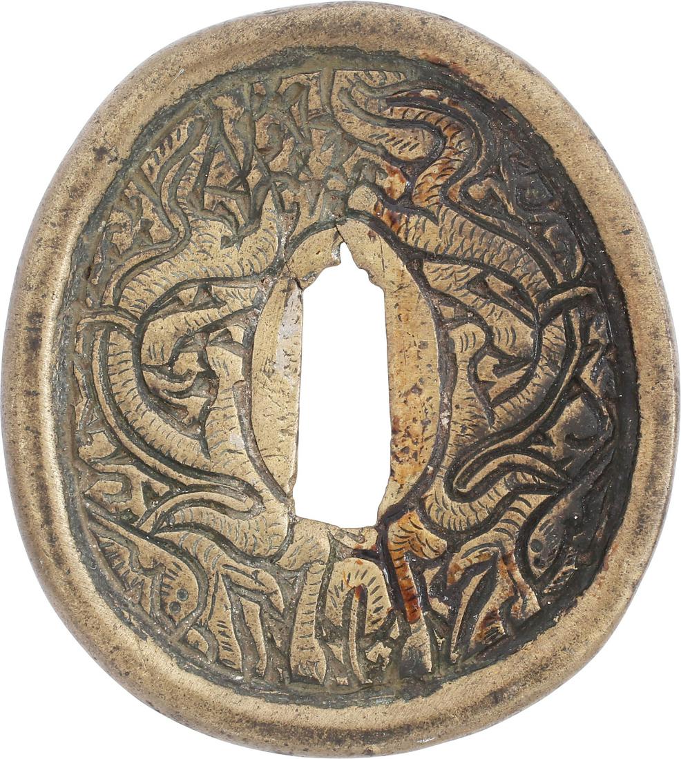JAPANEE SWORD GUARD TSUBA: Brass, oval form, 3” height. The front decorated in bold Buddhist dragon and cloud motif. The back plain. Mottled patina.