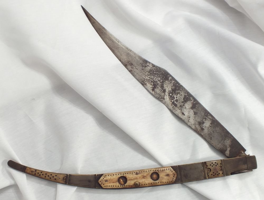 LARGE SPANISH FOLDING KNIFE NAVAJA: 18th-early 19th century. 11 3/8" clipped point blade with spring lock back mechanism. Brass side scales (slightly buckled) with laminated brass and pierced bone overlay. Dark patina.