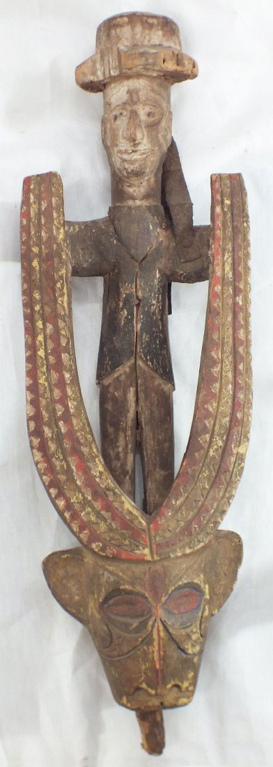 ANTIQUE IBO WOOD FIGURE EX. CHRISTIES LONDON: Standing male on a bush cow head, the horns incised and pigmented in hound’s tooth bands. The characterful face pigmented to match. The male in black waist coat with white pigmented face and hat inc