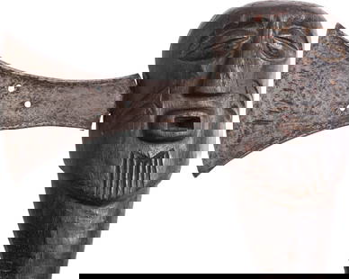 SONGYE SLAVER'S FIGURAL AXE: Finely forged blade with the hammer raised (coined) front and back and beveled edge. Pierced with three holes accentuated with sunburst markings. Wood haft carved with a human face with scarified chee