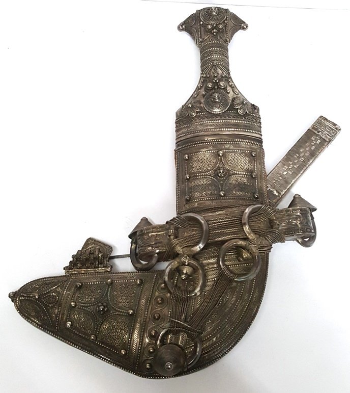 Traditional Omani Arabic Janbiya Khanjar Curved Dagger: A traditional Arabic janbiya or Omani khanjar with a stunning chased silver hilt and sheath. Includes small sheathed dagger. Total dimensions: 14in length x 10.25in width; curved dagger is 13in length