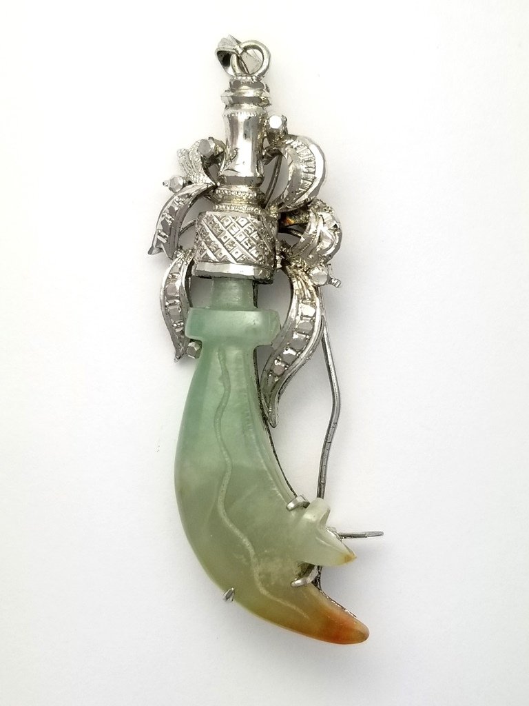 18k White Gold Fine Mutton Fat to Rust Jadeite Jade Car: 18k White Gold Fine Mutton Fat to Rust Jadeite Jade Carved Saber Sword Form Pendant Brooch Circa 1920s. Description:Offering an 18k White Gold Fine Mutton Fat to Rust Jadeite Jade Carved Saber Sword F