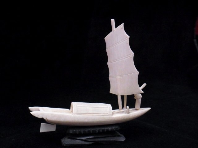 Carved Ivory Miniature Sailboat Waving Figure on D: Carved Ivory Miniature Sailboat Waving Figure on Deck 3.75” high 4.25” long Excluding Wooden Base Flags Fly Mast and Main Sail Fit in Place Description: This is a wonderful miniature sailboat wi