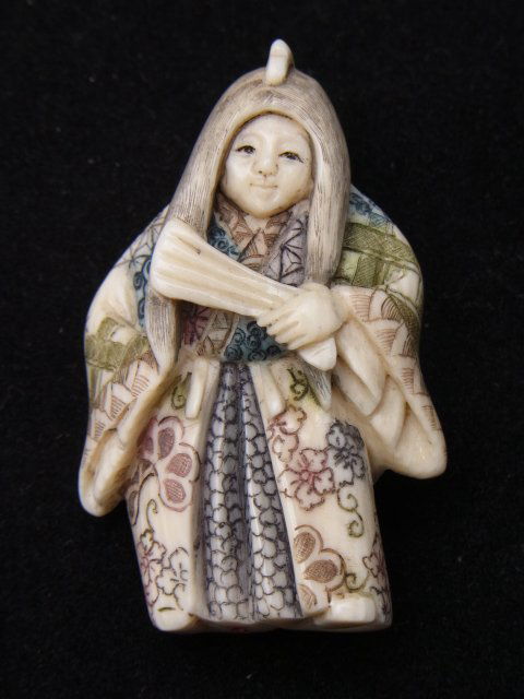 Signed Hand Carved Japanese Netsuke Figure Holding: Signed Hand Carved Japanese Netsuke Figure Holding Fan & Elaborate Hand Colored Kimono or Robe Possibly a Child Probably Showa Description: Beautifully colored and signed on base of feet as illustra