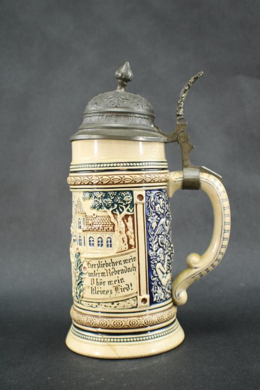 Antique Reinhold Merkelbach 1149 Beer Stein: Antique Reinhold Merkelbach Pottery Beer Stein with Pewter Lid, Model 1149 with Tan Blue, Brown, Green & Black Courting Scene in relief, with RM within a Star mark, "1149" and "Geschützt" on bottom, 