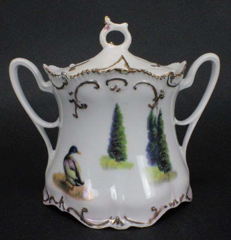 RS Prussia Duck Sugar Bowl with Hand Made Lid: Measures approximately 4.5 inches tall x 5.2 inches wide x 2.5 inches in diameter. Design depicts a duck in the foreground, with three trees in the distance. Piece has gold line work detail. Maker's m