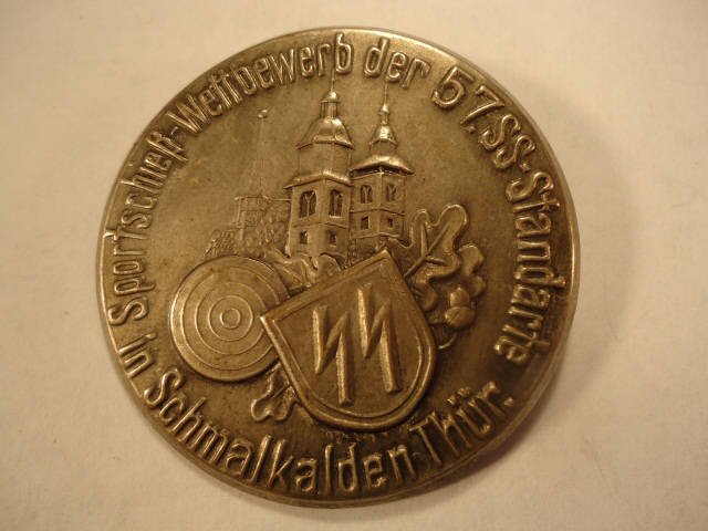 German World War II Waffen SS Tinnie Badge: German World War II Waffen SS Tinnie Badge. Measures 1 11/16 in diameter. Pin back. Maker marked 'Carl Peter Schmalkalden'. Stamped nickel construction"