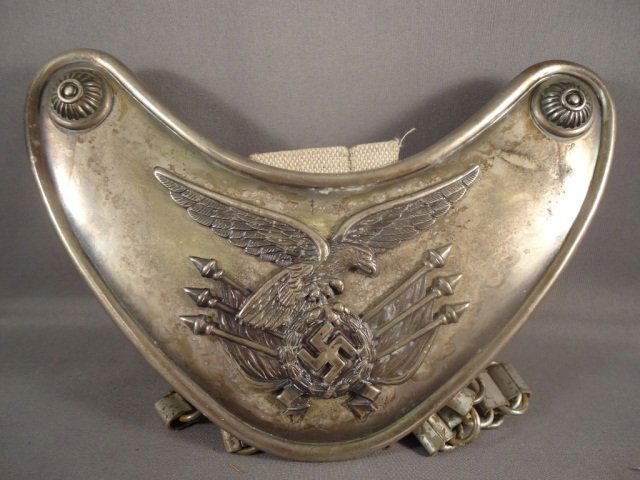 WWII Luftwaffe Standarte Flag Bearer Gorget: German World War II Luftwaffe Regimental Standarte Flag Bearers Gorget. Measures 4 1/2 tall by 7 1/16" wide. The center tab on the reverse side is maker marked 'Assmann'. Includes the steel neck chain