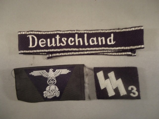 German WW II Waffen SS Deutschland EM Cuff Title: German World War II Waffen SS Deutschland EM Cuff Title. Measures 1 1/8" by 17 7/8". Also included is an SS # 3 collar tab + an SS eagle and skull bevo cap insignia. All for an enlisted man.