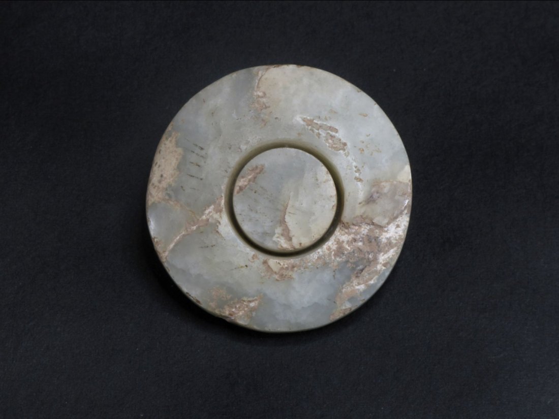 A Chinese Jade Sward Ornament, Han Dynasty: Of circular form, fashioned in to a disk with an openwork inner ring. D: 4.5 cm