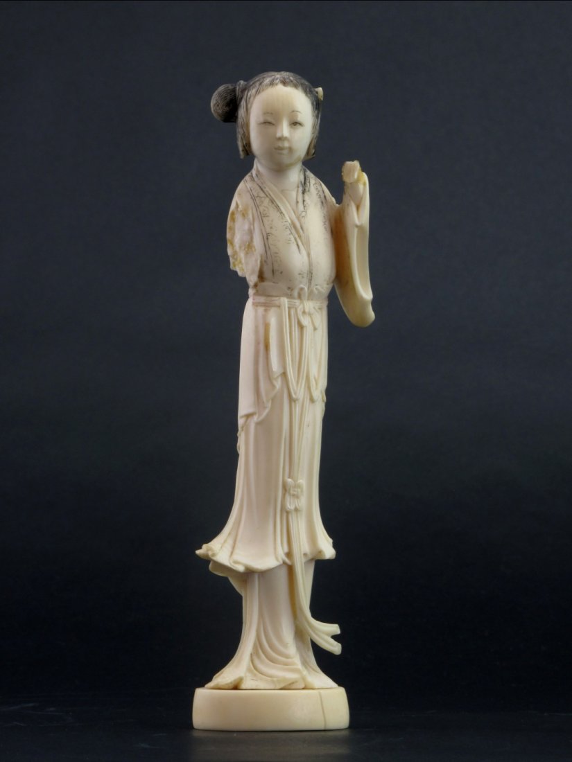 A Chinese Carved Ivory of a Beauty: Small intricately carved female figure on stand, most likely either bone or ivory. Large cracks on figure, missing hands and some color are faded. H: 17.8 cm