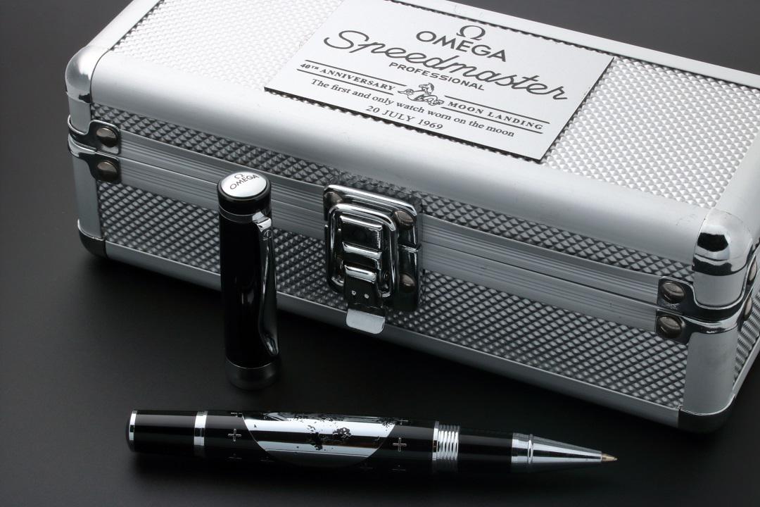 Omega Speedmaster 40th Anniversary Apollo 11 Moon Pen: Very fine Omega Speedmaster Professional 40th Anniversary Apollo 11 Moon Landing ballpoint pen with flight case. Black barrel with silver graphics depicting the moon with the words “Landing Site: 