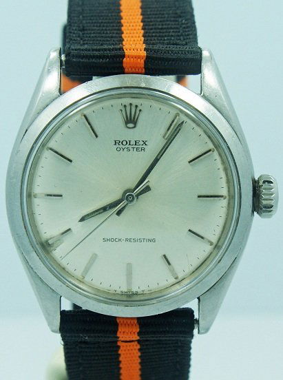 Stainless Steel Rolex Oyster Shock Resisting Watch: Stainless steel Rolex Oyster watch, ref #6480, circa 1955. Silver dial with bar hour markers. The dial says "Shock Resisting." Case diameter is approximately 37mm with the crown.