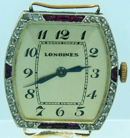 18k Yellow Gold Longines Watch with Diamonds and Ru: 18k yellow gold Longines wristwatch with diamonds and rubies. Silver dial with painted black Arabic numerals. Hinged case with an engraved leaf motif around the sides. Diamond and ruby bezel. The crow