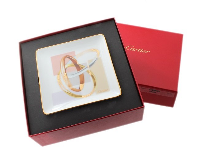 Cartier Trinity Mini Tray Limoges France with Box: Cartier Trinity Mini Porcelain tray Limoges France with original Cartier fitted box and ribbon. The tray has an image of the Cartier gold Trinity rings. It`s approximately 4-5/8 in x 4-5/8 in.