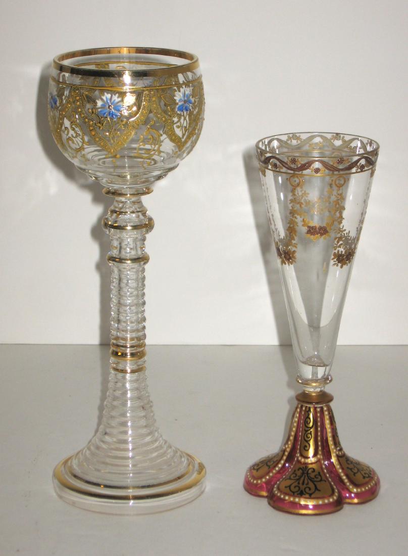 Two Moser decorated glass goblets,: The first a cranberry clover base trumpet flute with enameled bows and flower swags, together with a tall wine with beehive stem decorated with six gilt Moorish panels of a single blue flower, tallest