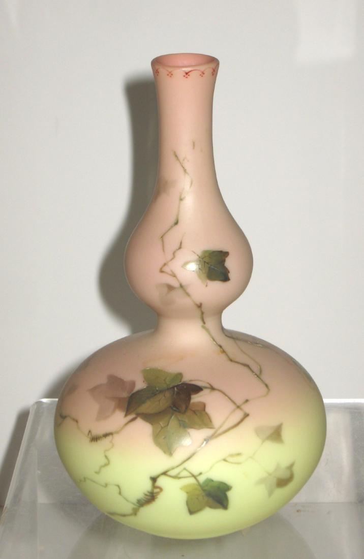 Webb Burmese decorated glass vase,: Gourd stick vase in cream shading to rose decorated with a cascading leafy ivy, accepted with a crimson scrolling enameled rim, acid marked Thomas Webb and Sons, 7" ht. CONDITION: Good with no chips c