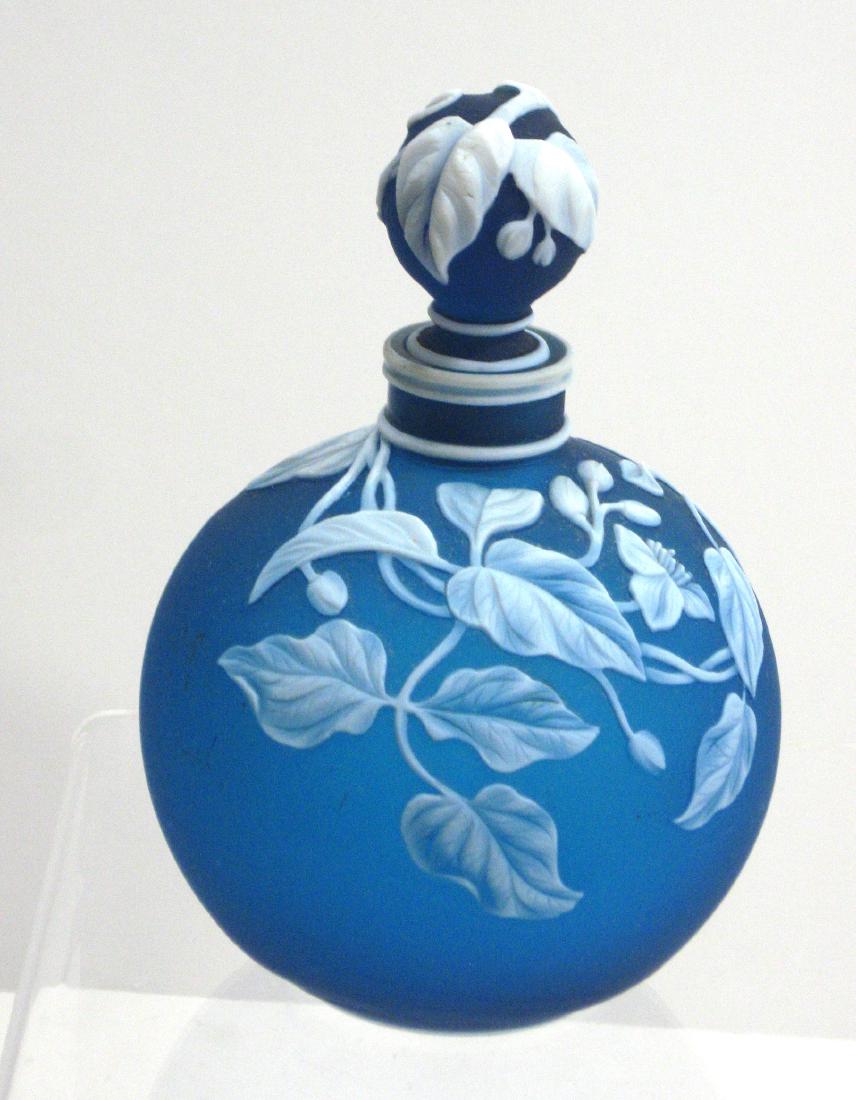 Webb Prussian blue English cameo perfume,: Ovoid form in blue glass decorated with a cascading flowering vine and a butterfly on the reverse adorned with a decorated stopper, singed Thomas Webb and Sons, 6" ht. Condition: chip to the white ban