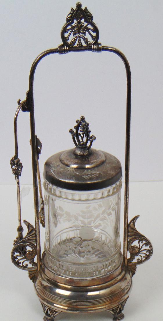 Etched floral pickle castor: Clear glass jar with etched flower set in a Pairpoint caddy, 13" ht. Condition: good with no defects found