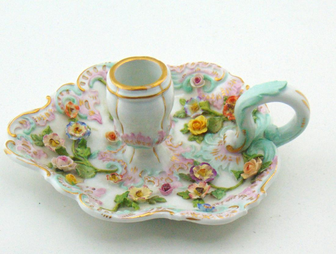 Meissen candlestick: Leaf form candlestick with finger holder adorned with applied flowers, cross sword mark, 6" long. Condition: minor repair to some flowers.