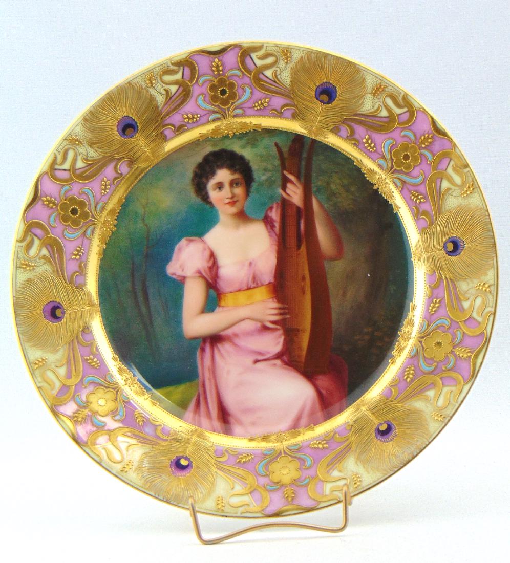Royal Vienna porcelain plate: Central pictorial medallion of a young woman playing a lute, titled "Ein Lied" or A Song, framed with a pink and tan border with gold and purple peacock eyes, marked with the beehive factory back stam