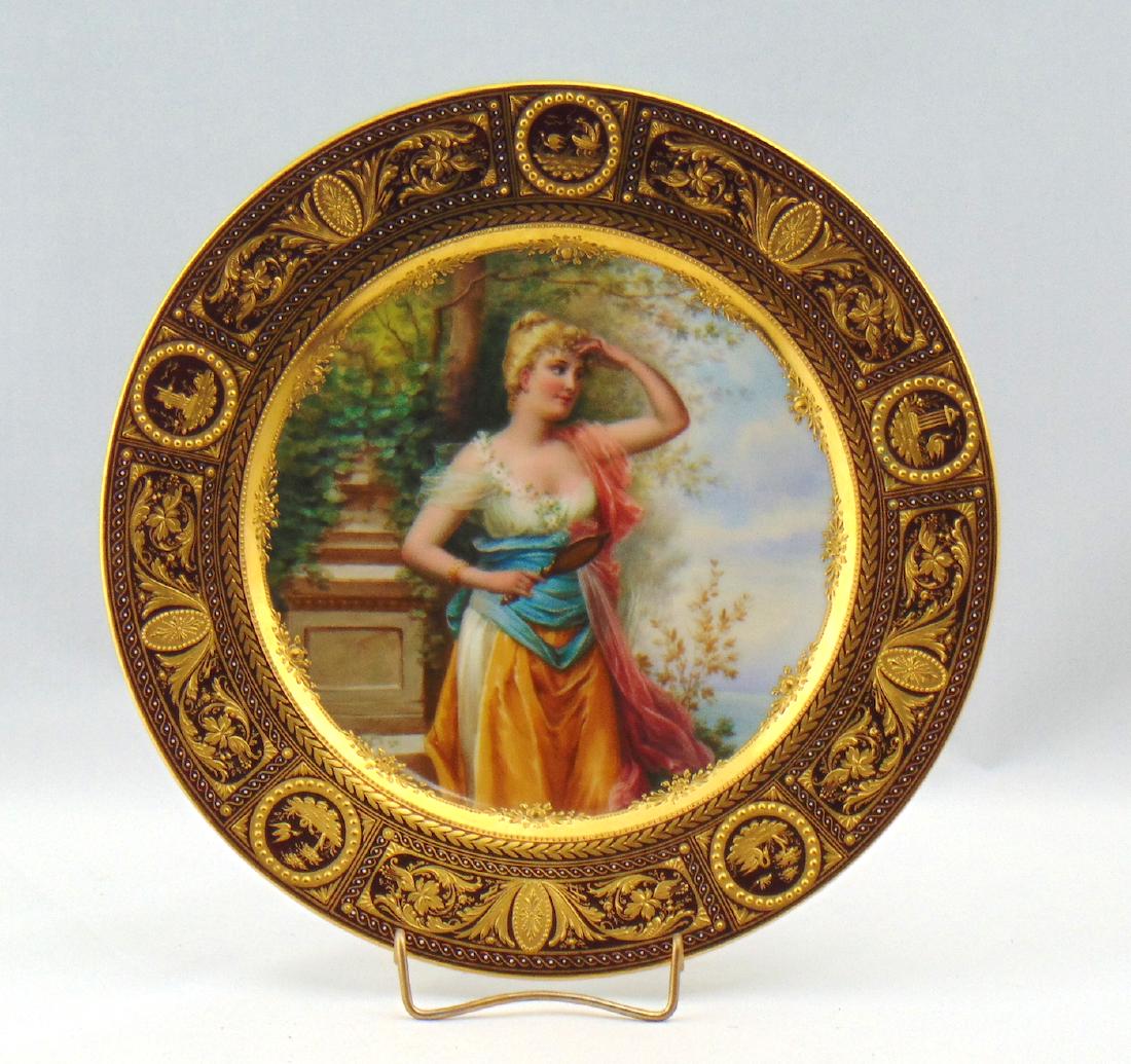 Royal Vienna porcelain plate: Ruby "Vanity" plate with framed gold scrolling adorned with a central portrait medallion of a young women in a Garden, marked with the blue beehive back stamp, 9 1/2" wide. Condition: good with no def