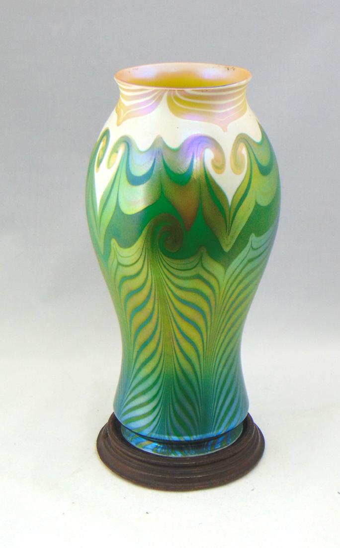 Quezal art glass lamp base: Shouldered form in green to opal glass decorated with an iridescent gold hook feather design set on a removable wood base, glass only 12 1/2" ht. Condition: good with no defects found.