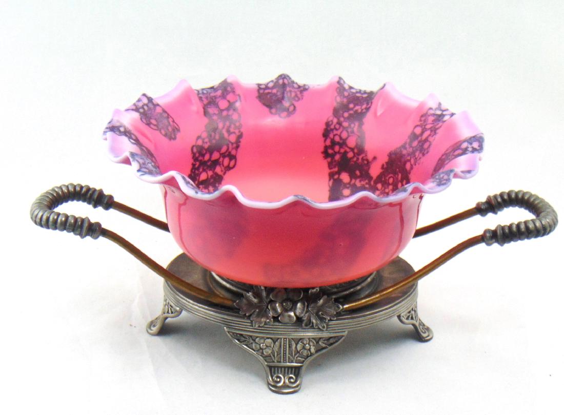 New England Agata Brides basket: New England Wild Rose ruffled rim bowl decorated with random bands of purple Agata, set in a two handle marked Pairpoint silver-plate caddy, bowl 9" wide. Overall with base 13 1/2" long. Condition: go