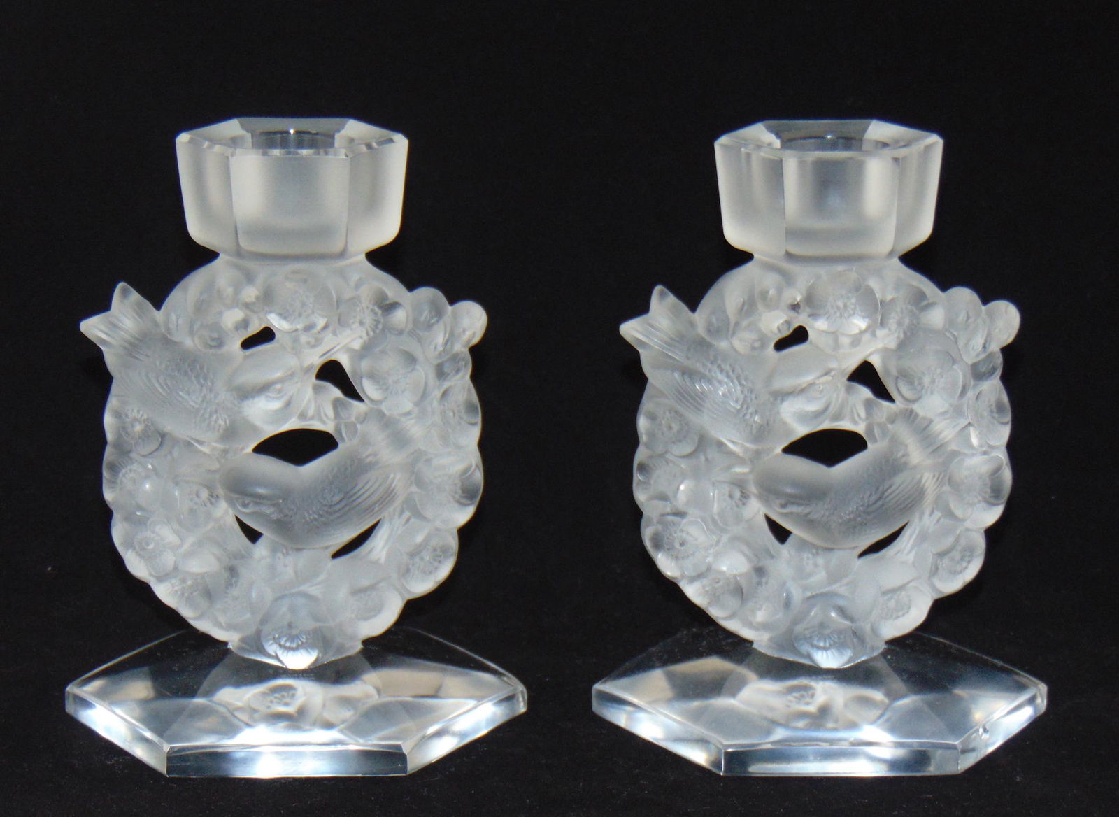 Pair of Lalique candlesticks: Pair of Lalique candlesticks each with a circular wreath and song birds, signed Lalique France, 5 1/2" ht. Condition: one with chip to the foot rim, one with minor chip to candle rim, see pictures